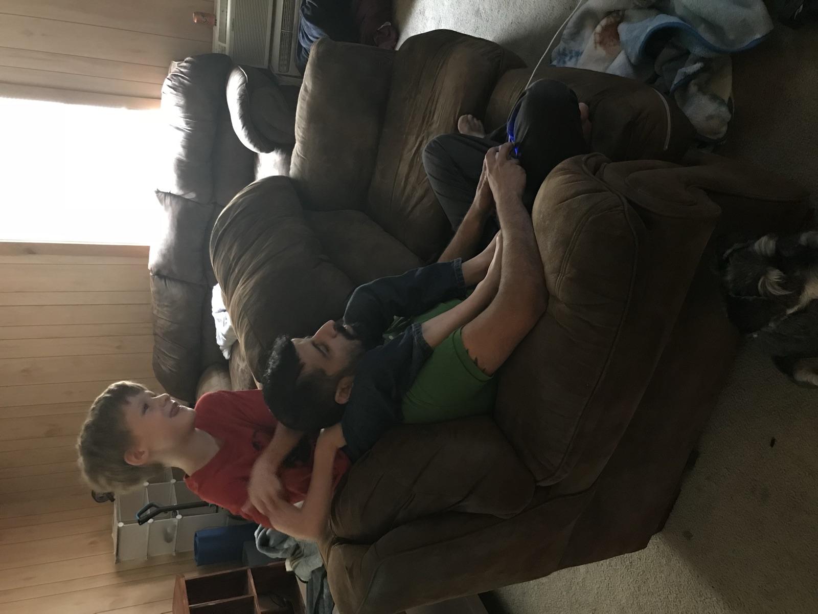 A young boy leaning on Sohail's shoulder on the couch