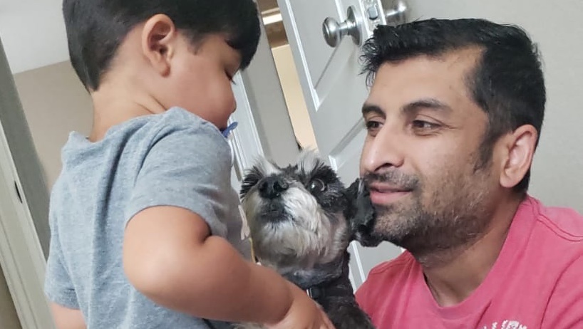 Sohail Moiz smiling with a toddler and the family dog